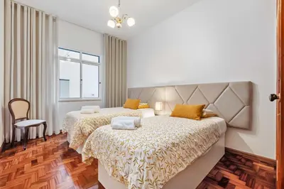 a bedroom with two beds and a chair at Casa dos Leões in Arco da Calheta