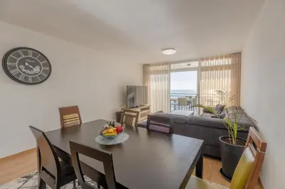a living room with a dining table and a clock at flowers island house 8 infinity in Funchal