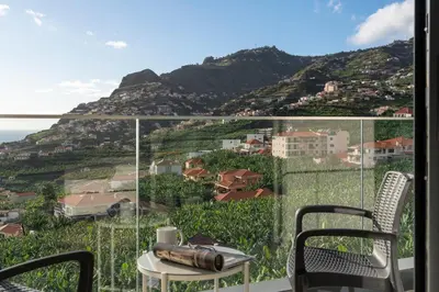 a balcony with a table and chairs and a mountain at Saraiva Hills I by An Island Apart in Câmara de Lobos