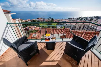 a balcony with chairs and a table and the ocean at SkyView Penthouse Apartment in Caniço
