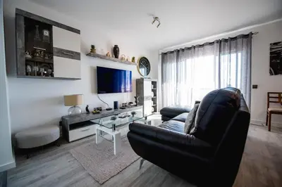 a living room with a black leather couch and a television at SkyView Penthouse Apartment in Caniço