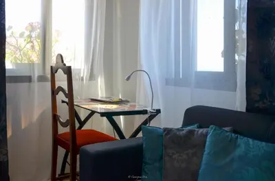 a living room with a table and a chair and a table with a lamp at Teixeira House in Arco da Calheta