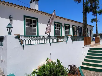 a white building with a fence and a sunset at Casa da VíVí in Azenha de Baixo
