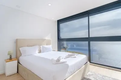 a bedroom with a white bed with a large window at GuestReady - Madeiran oasis with ocean view in Campanário