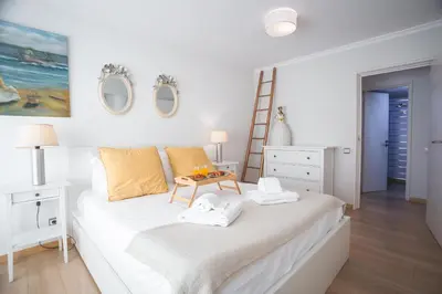 a white bedroom with a bed and a table at Tropical Sun by Atlantic Holiday in Funchal