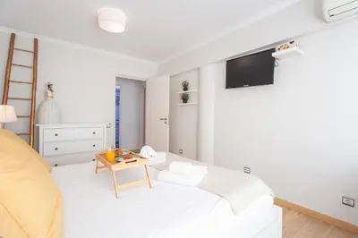 a white bedroom with a bed and a table at Tropical Sun by Atlantic Holiday in Funchal