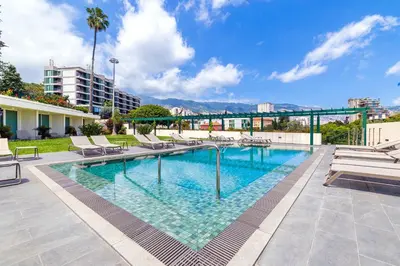 a swimming pool with lounge chairs and a building at Pestana Quinta Perestrello in Funchal