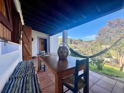 a dining room with a table and a large window at Entre a Serra e o Mar - Casa das Rosas de Barão in Barão de São João