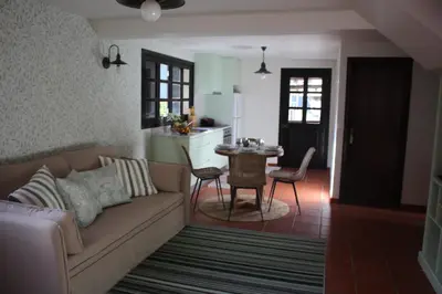 a living room with a couch and a kitchen with a table at Casa dos Lamaceiros in São Vicente