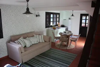 a living room with a couch and a kitchen at Casa dos Lamaceiros in São Vicente