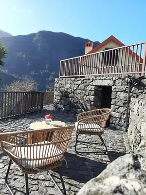 two chairs and a table on a patio with a stone fireplace at Casa dos Lamaceiros in São Vicente