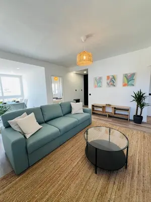 a living room with a blue couch and a glass table at Arrifana Sunrise & Mountain View in Aljezur