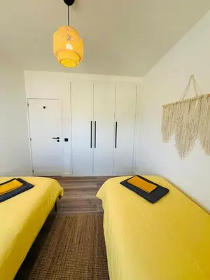 two beds in a room with yellow sheets at Arrifana Sunrise & Mountain View in Aljezur