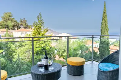 a balcony with a table with a glass of wine at Las Rosas Vista Baia do Funchal in Funchal
