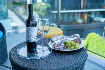 a table with a bottle of wine and a plate of grapes at Las Rosas Vista Baia do Funchal in Funchal