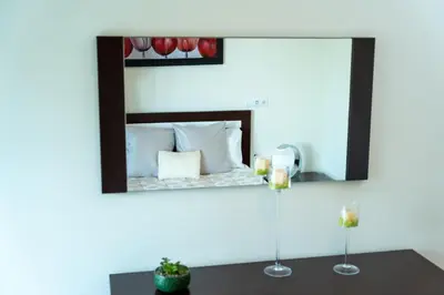 a mirror on a wall above a bed with two candles at Las Rosas Vista Baia do Funchal in Funchal