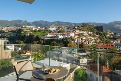 a table and chairs on a balcony with a view of a city at Maravilhas I by An Island Apart in Funchal