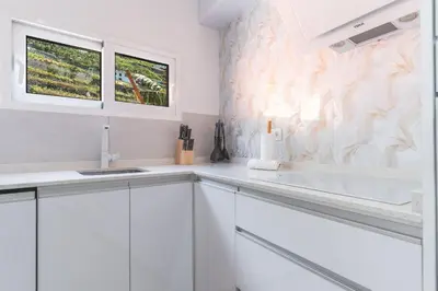 a white kitchen with white cabinets and a window at Atlantic Lookout by Atlantic Holiday in Calheta