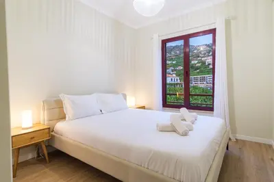 a bedroom with a white bed and a window at GuestReady - Charming home in Câmara de Lobos in Câmara de Lobos
