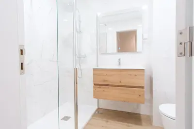 a white bathroom with a shower and a sink at GuestReady - Charming home in Câmara de Lobos in Câmara de Lobos