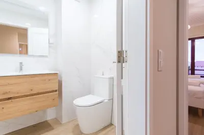 a white bathroom with a toilet and a sink at GuestReady - Charming home in Câmara de Lobos in Câmara de Lobos