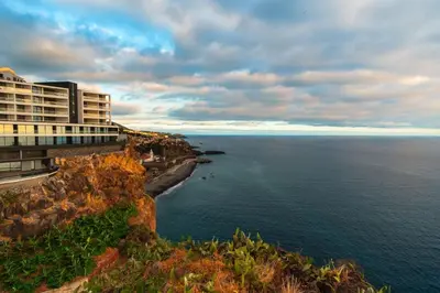 a building on a cliff next to the ocean at GuestReady - Charming home in Câmara de Lobos in Câmara de Lobos
