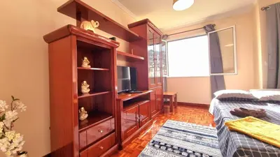 a bedroom with a bed and a cabinet with a television at Perfume a Maresia in Câmara de Lobos
