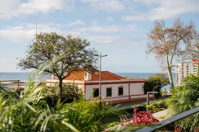 a view of a building with trees and the ocean at Savoy Monumentalis your home in Madeira Island in Funchal