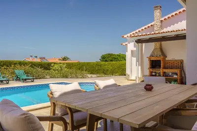 a wooden table and chairs next to a swimming pool at Sunny Ocean Villa with pool near Arrifana beach in Aljezur