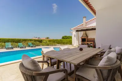 a wooden table and chairs next to a swimming pool at Sunny Ocean Villa with pool near Arrifana beach in Aljezur