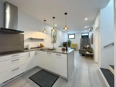 a kitchen with white cabinets and a living room at City Center House in Funchal