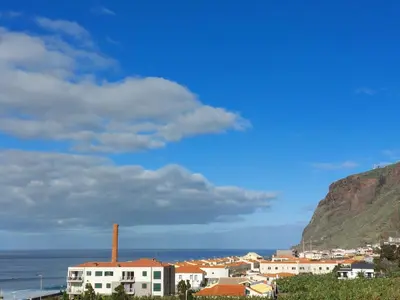 a building next to the ocean with two flags at Studio Casa Tropicana in Paul do Mar