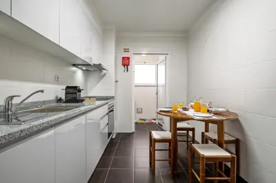 a small kitchen with a table and chairs in it at Refúgio Girassol in Caniço