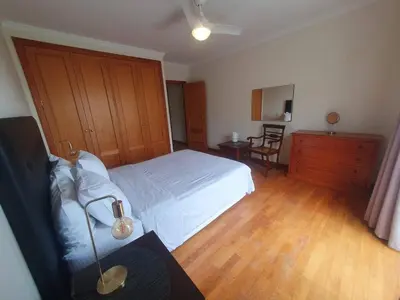 a bedroom with a white bed and a wooden floor at Aqua Vista Lido Apartment in Funchal