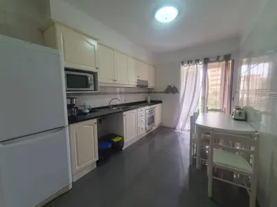 a kitchen with white cabinets and a table in it at Aqua Vista Lido Apartment in Funchal