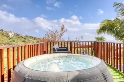 a hot tub on a deck with a wooden fence at Ricardo House, a Home in Madeira in Calheta