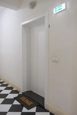 a white hallway with a exit sign on a checkered floor at Modern City Apartment Funchal in Funchal