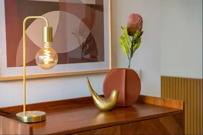 a table with a vase with a flower and a lamp at Modern City Apartment Funchal in Funchal