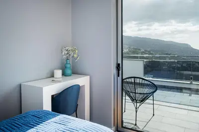 a bedroom with a bed and a chair on a balcony at Casa da Lombada in Ponta do Sol