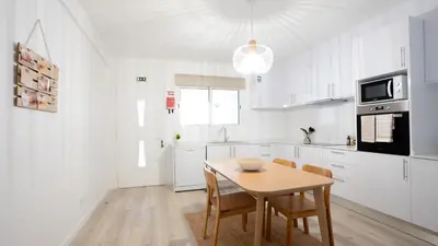 a white kitchen with a wooden table and chairs at Amaro Oasis by LovelyStay in Funchal