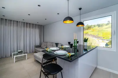 a kitchen and living room with a table and a couch at Radiantescapadela in Estreito da Calheta