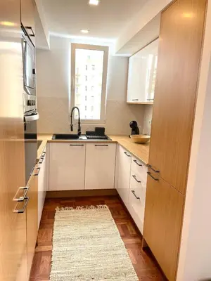a kitchen with white cabinets and a sink and a rug at Island Time Studio with Sea View in Funchal