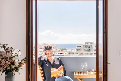 a woman sitting on a window sill reading a book at Funchal Heritage Studio in Funchal