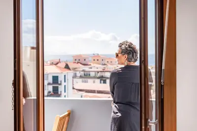 a woman standing on a balcony looking out the window at Funchal Heritage Studio in Funchal