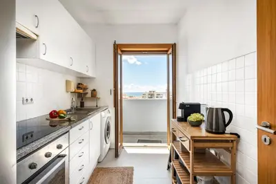 a kitchen with white appliances and a large window at Funchal Heritage Studio in Funchal