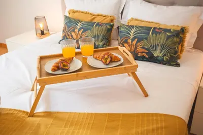 a tray of food and two glasses of orange juice on a bed at Sao Pedro Central Flat by Atlantic Holiday in Funchal
