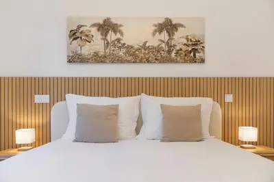 a bedroom with a bed with white pillows and palm trees at Uptown II by An Island Apart in Funchal