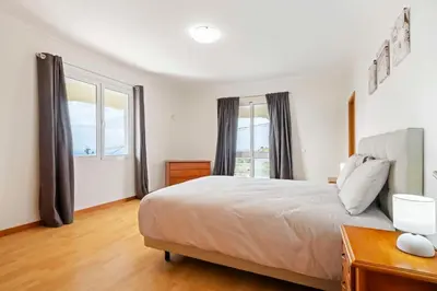 a bedroom with a bed and a large window at SunRise Vila in Estreito da Calheta