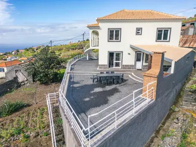 a house on a retaining wall with a picnic table at SunRise Vila in Estreito da Calheta