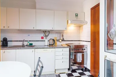 a kitchen with white cabinets and a checkered floor at GuestReady - A homely retreat in São Martinho in Funchal
